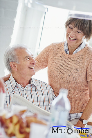 Stock Photograph - Elderly couple laughing at a newspaper article